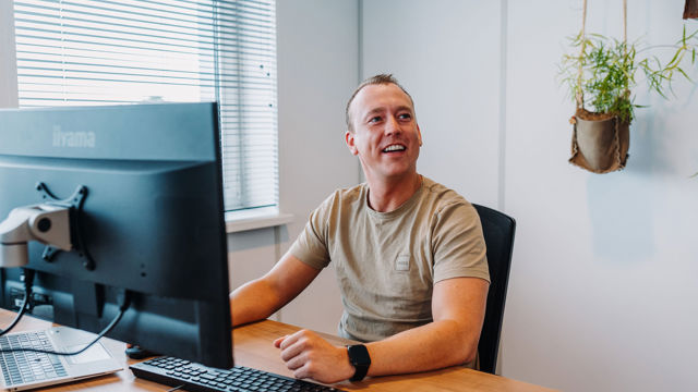 Mdw lachend achter bureau